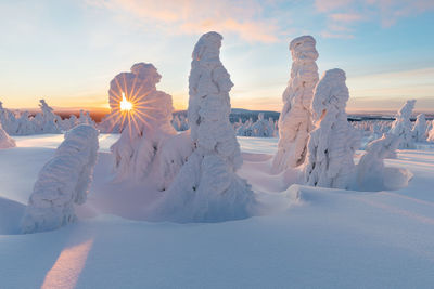 Snow covered landscape against sky during sunset