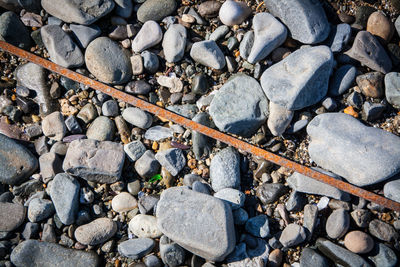 High angle view of rusty metallic rod over pebbles