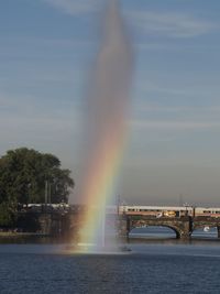 Scenic view of rainbow over river against sky