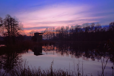 Silhouette trees by lake against sky during sunset