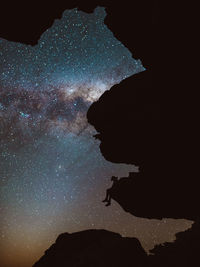Low angle view of silhouette mountain against sky at night