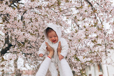 Full length of cute baby girl with cherry blossom tree