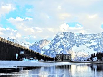 Scenic view of lake by snowcapped mountains against sky