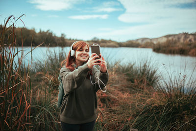 Full length of man photographing while standing on lake