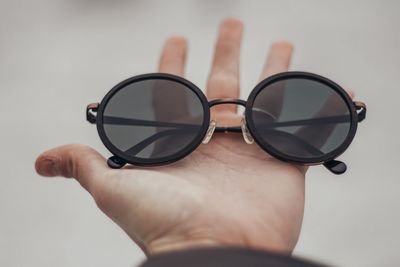 Close-up of hand holding eyeglasses against white background