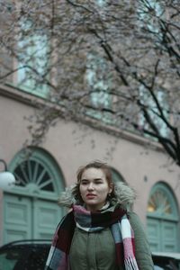 Woman looking away against building and tree