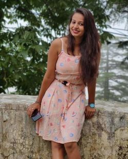 Beautiful young woman smiling while standing against stone wall