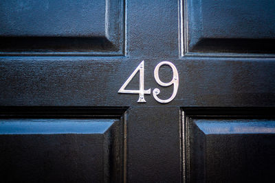 House number 49 on a dark wooden front door in london 