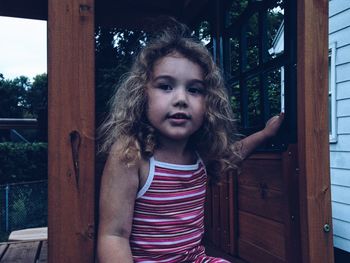 Cute girl sitting at entrance of log cabin