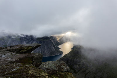 Scenic view of land and mountains in foggy weather