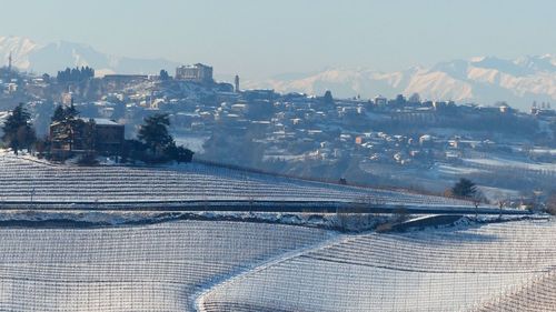 Aerial view of snow covered buildings in city against sky