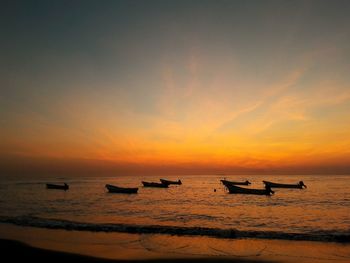 Silhouette boats in sea against sky during sunset