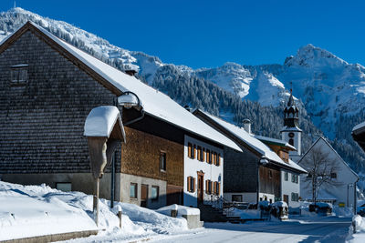 Houses by snow mountains against sky