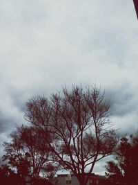 Low angle view of bare tree against cloudy sky