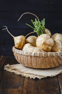 Close-up of yams in wicker basket on wooden table