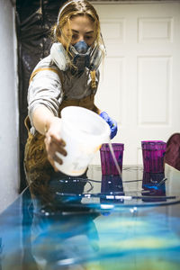 Female resin artist pouring with respirator mask