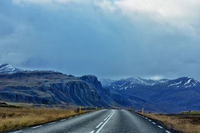 Road leading towards mountains against sky