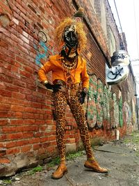 Young woman standing against brick wall