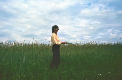 Girl standing in wheat field against sky