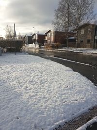 Snow covered houses by building against sky