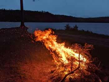 Bonfire by lake against sky at night