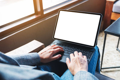 A woman using and typing on tablet keyboard with blank white desktop screen as a computer pc