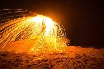 Firework display over sea against sky at night