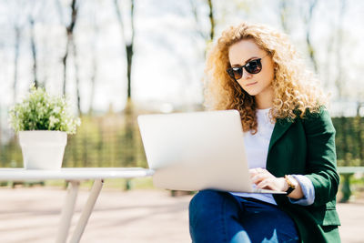 Young woman using mobile phone while sitting outdoors