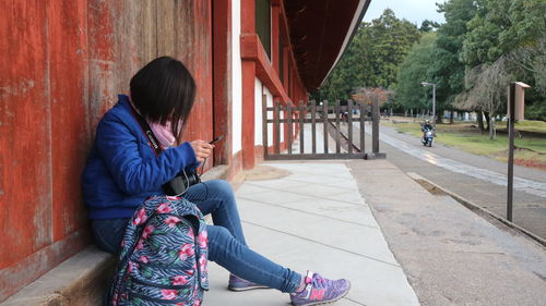 Side view of woman using mobile phone outdoors