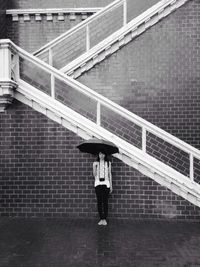 Full length of woman standing on railing during rainy season