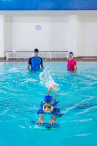 Boy swimming while instructors standing in background