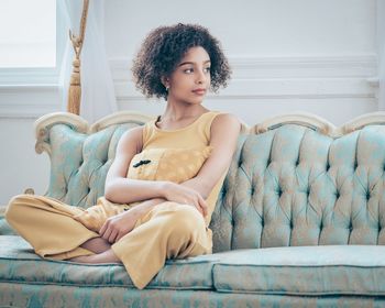 Beautiful young woman sitting on sofa at home