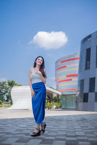 Portrait of young woman standing against sky