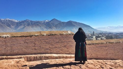 Rear view of woman standing against surrounding wall