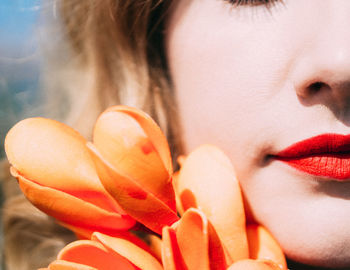 Close-up portrait of beautiful young woman with blond hair and orange flower