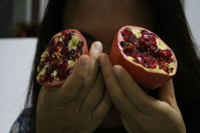 Close-up of covering face with pomegranates