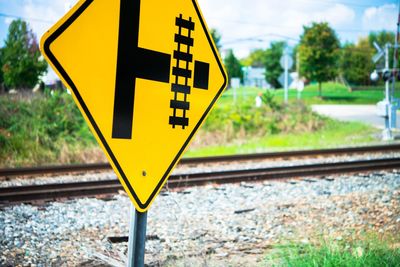 Close-up of road sign against railroad tracks