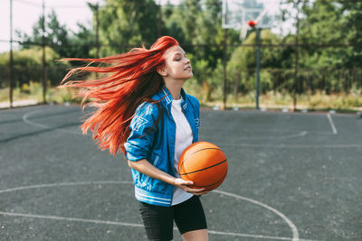 A young basketball player is training on an outdoor basketball court