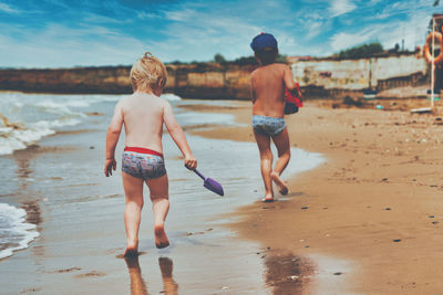 Rear view of shirtless boy on beach