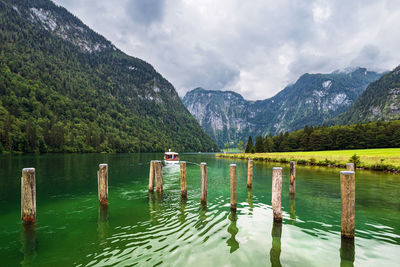 Wooden posts in lake against mountains