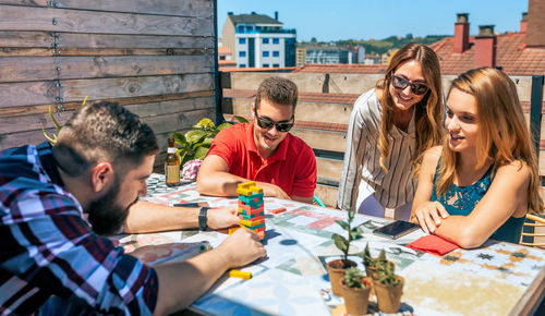 Bearded man catching jenga game piece next to colleagues on terrace