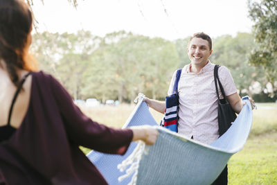 Couple placing blanket on field at park