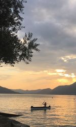 Woman rowing boat on lake during sunset