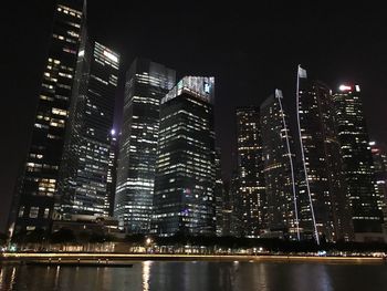 Illuminated city by buildings against sky at night