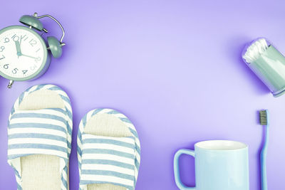 Close-up of slipper with cup and toothbrush over purple background