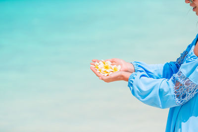 Midsection of woman holding ice cream against blue sky