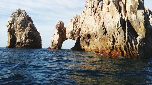 Scenic view of large rocks in sea against sky