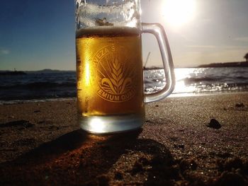 Close-up of beer glass on table against sea
