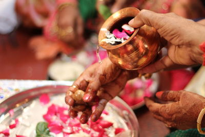 Close-up of hand holding indian wedding item in vessel