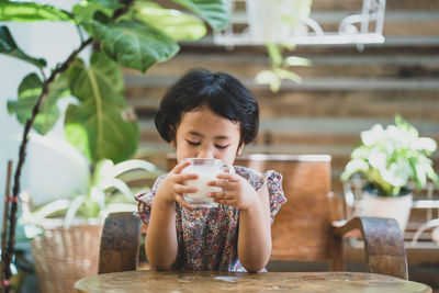 Full length of a young man drinking glass on table at restaurant